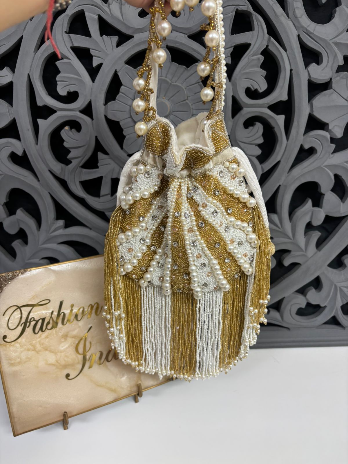 Decorative handbag with tassels and pearls on a decorative background with 'Fashion' text.