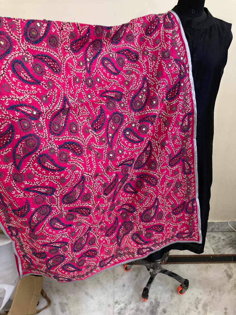 Pink and purple paisley patterned fabric draped over a black garment on a marble floor.