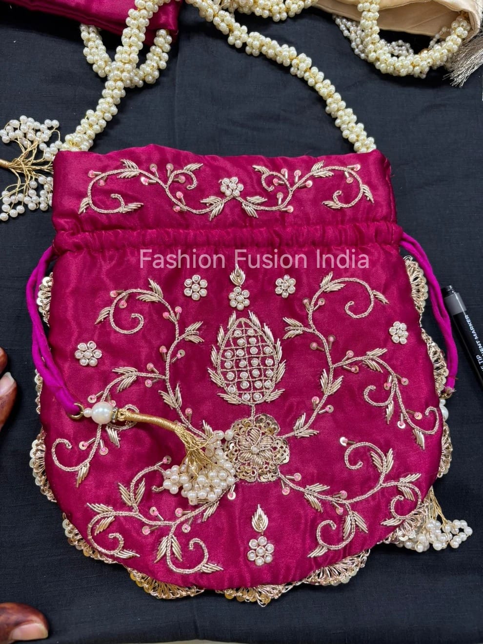 Pink embroidered bag with gold detailing on a dark surface, branded 'Fashion Fusion India'.