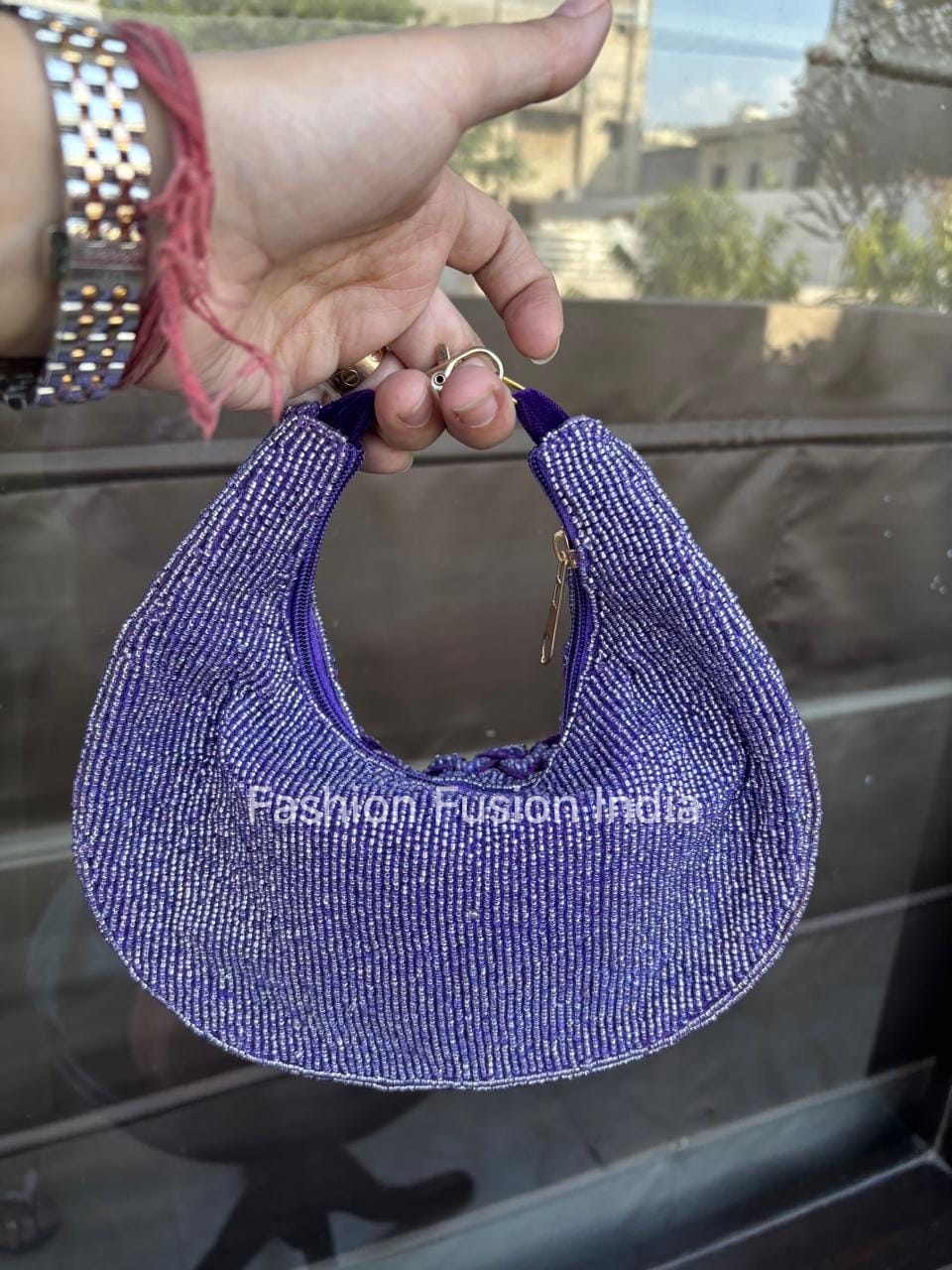 Purple beaded visor held by a hand with a blurred background