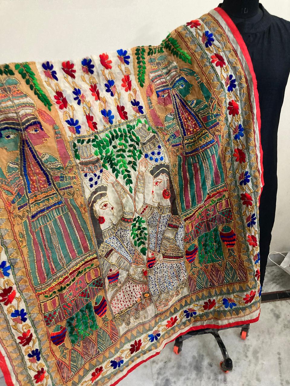 Colorful embroidered fabric on a mannequin against a neutral background