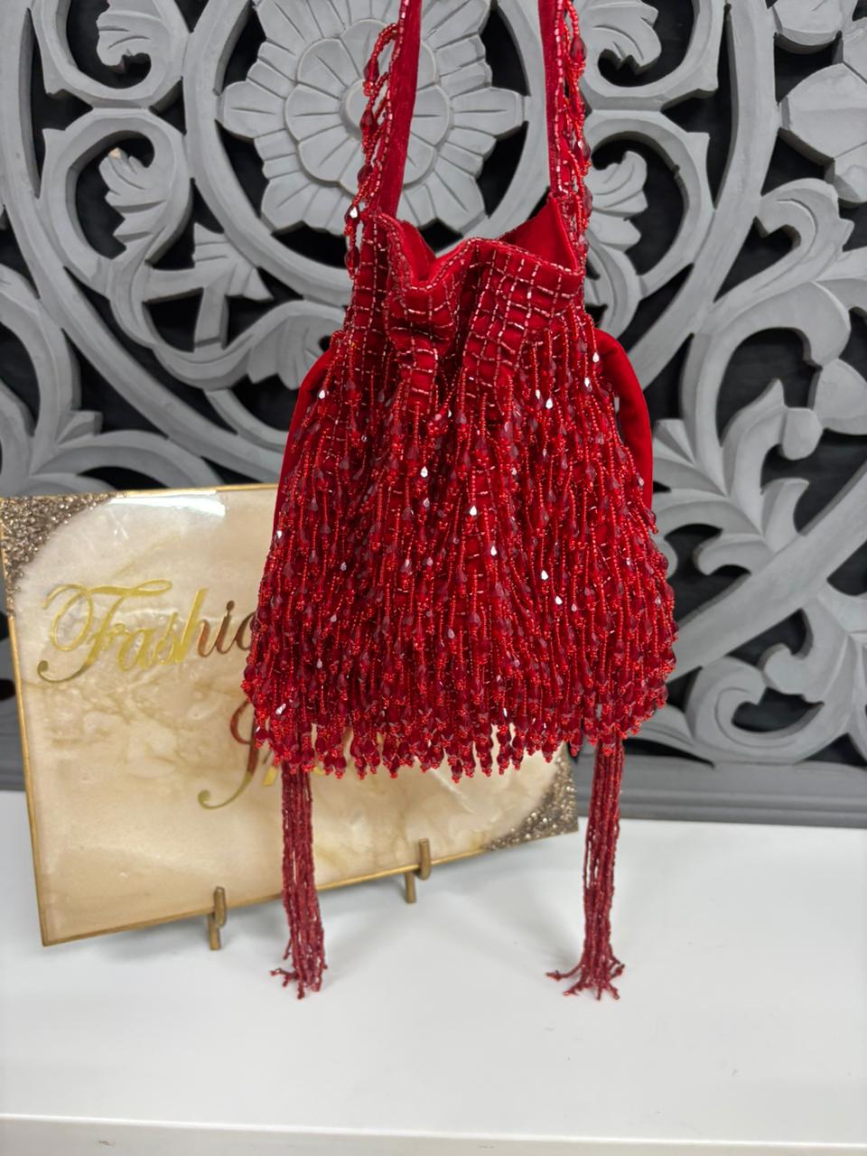 Red beaded handbag on a stand with decorative background