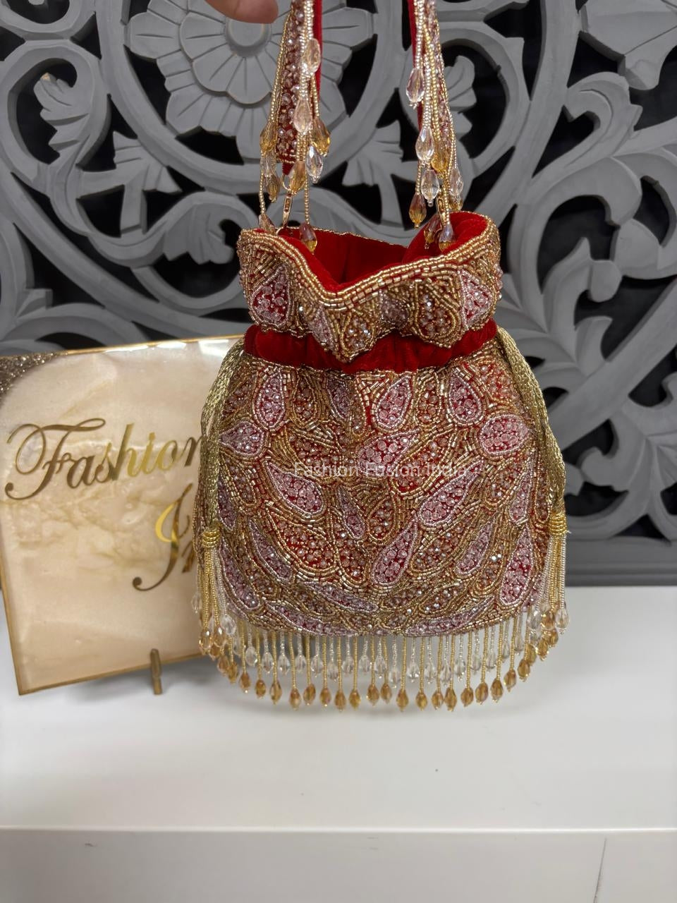 Decorative handbag with intricate patterns and gold accents on a white surface with 'Fashion' branding.