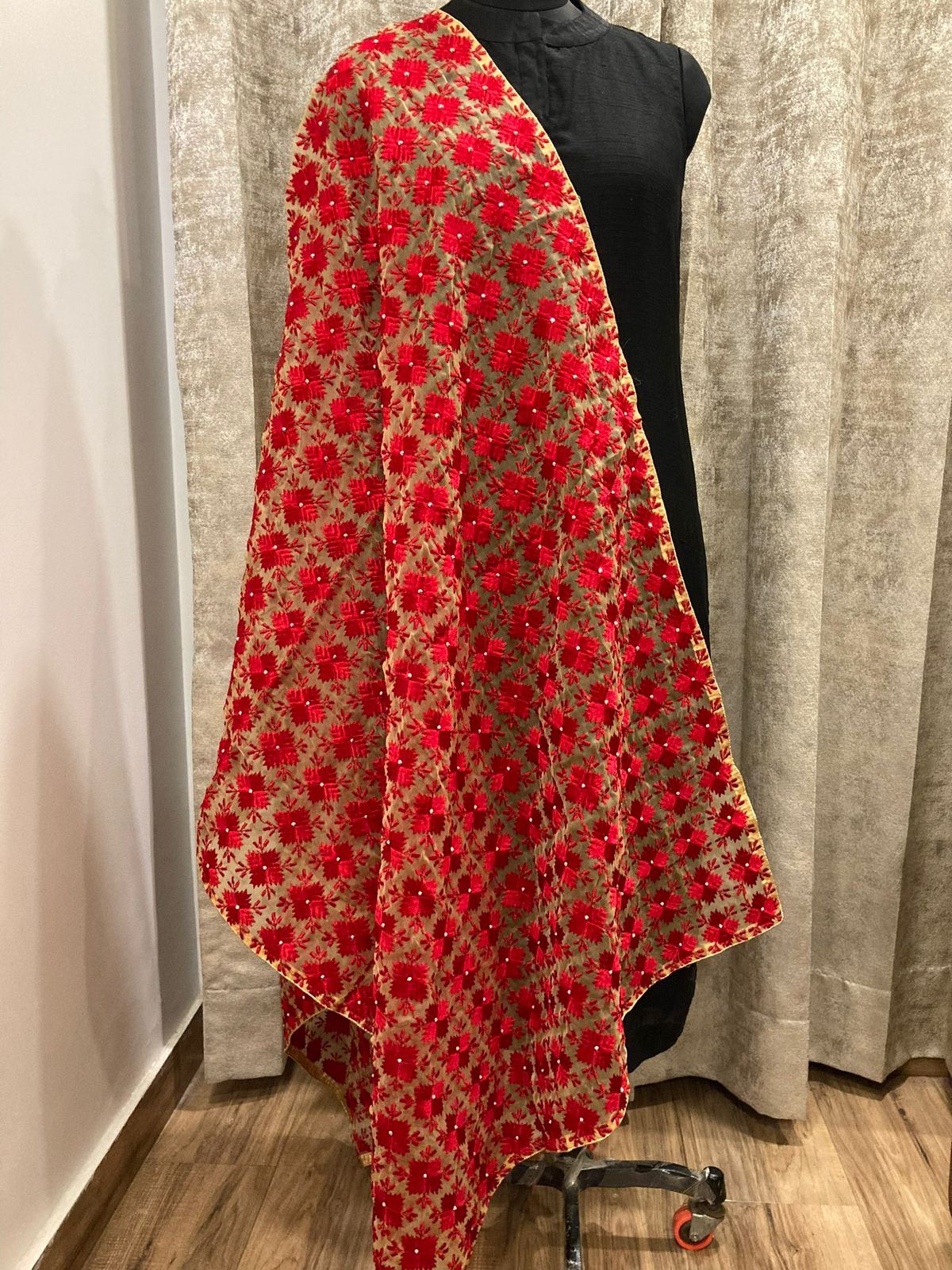 Red floral patterned fabric draped over a mannequin against a neutral background