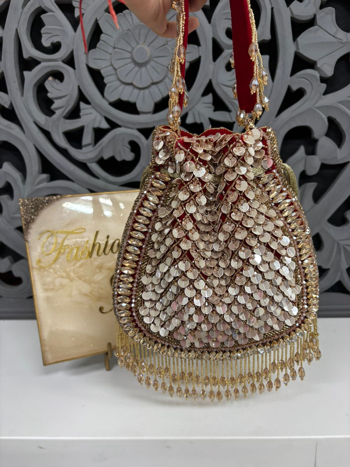 Decorative handbag with beaded details on a white surface with a decorative background