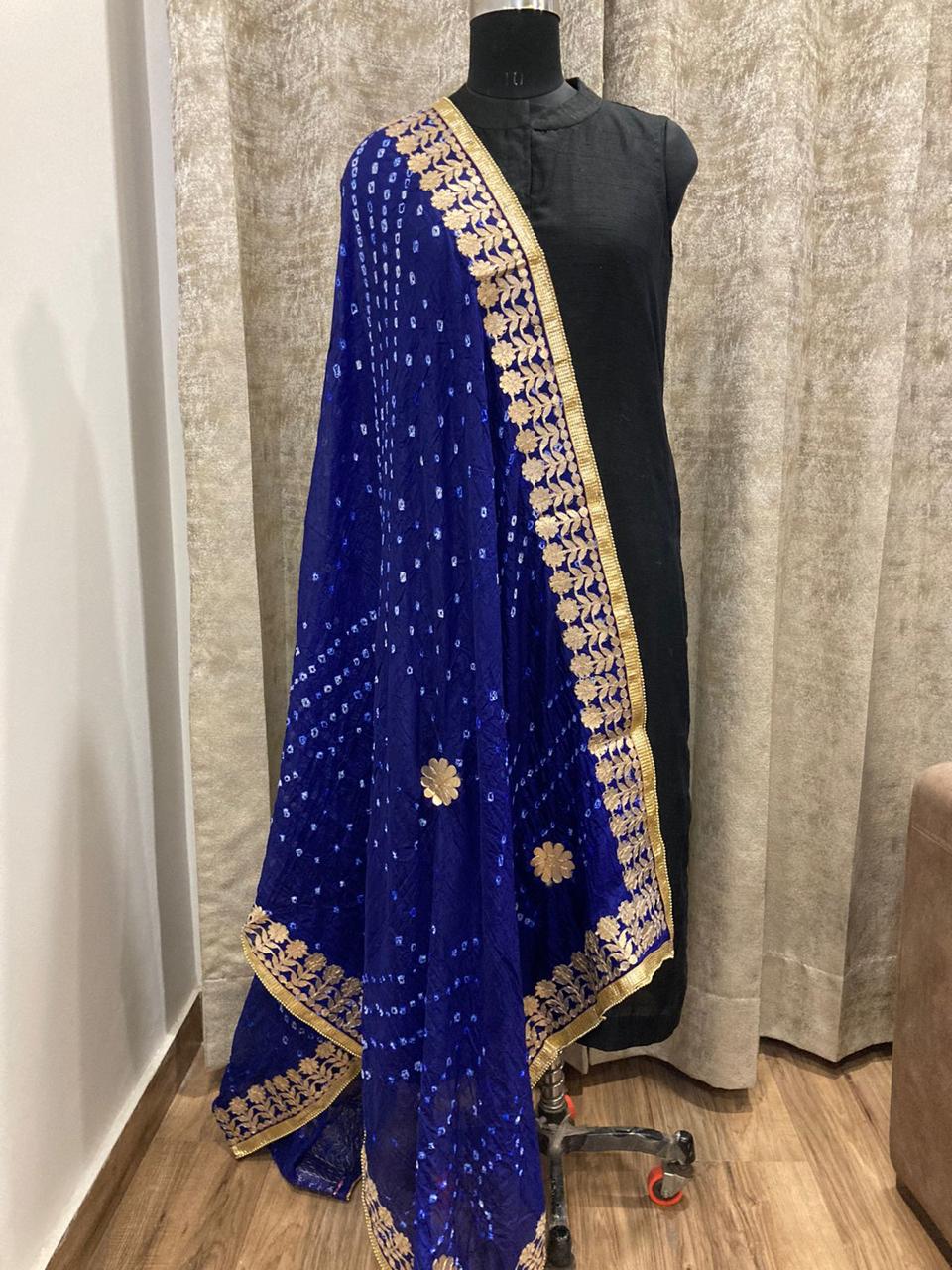 Blue embroidered saree with gold border on a mannequin against a neutral curtain background