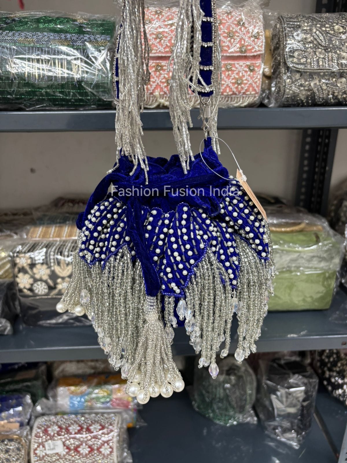 Decorative bag with blue velvet and pearl tassel details on a shelf.