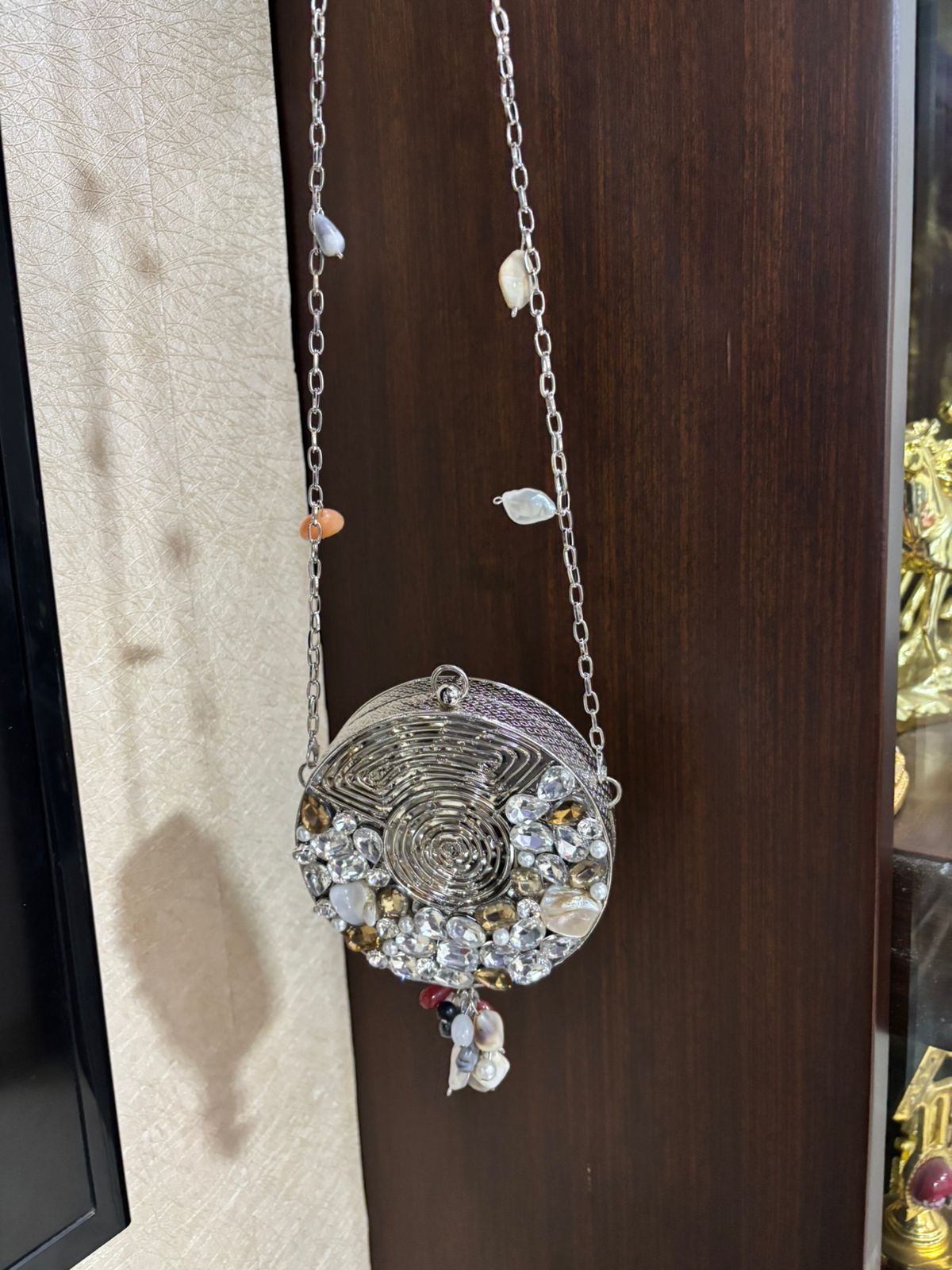 Decorative necklace with intricate design hanging against a wooden background