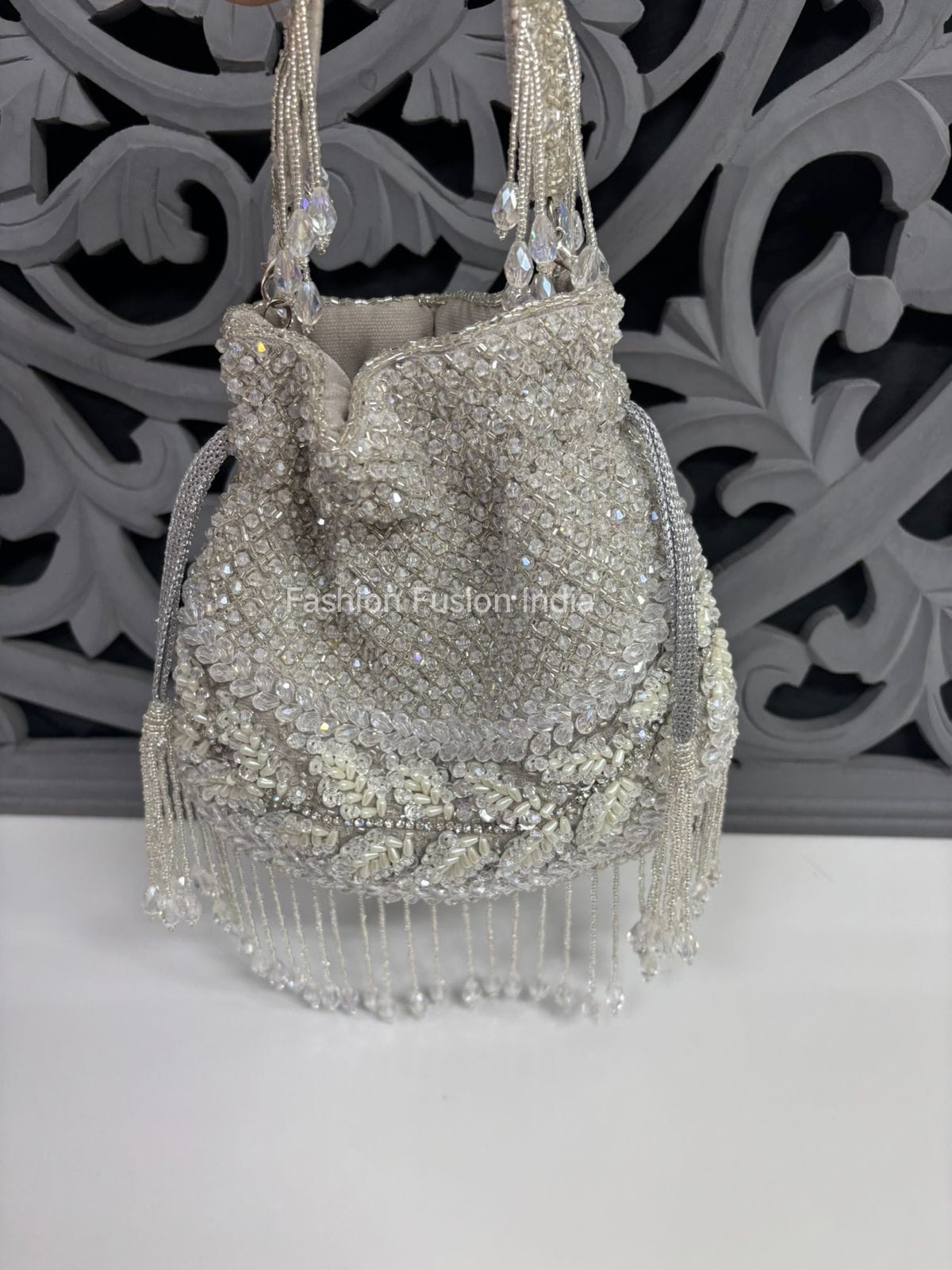 Silver beaded handbag with fringe on a decorative background