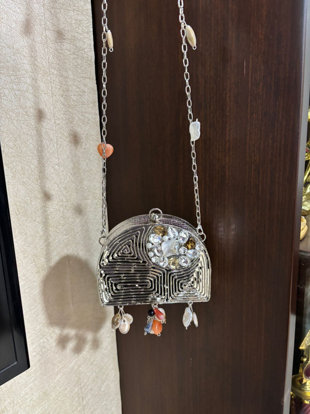 Decorative silver pendant with gemstones on a chain against a wooden background