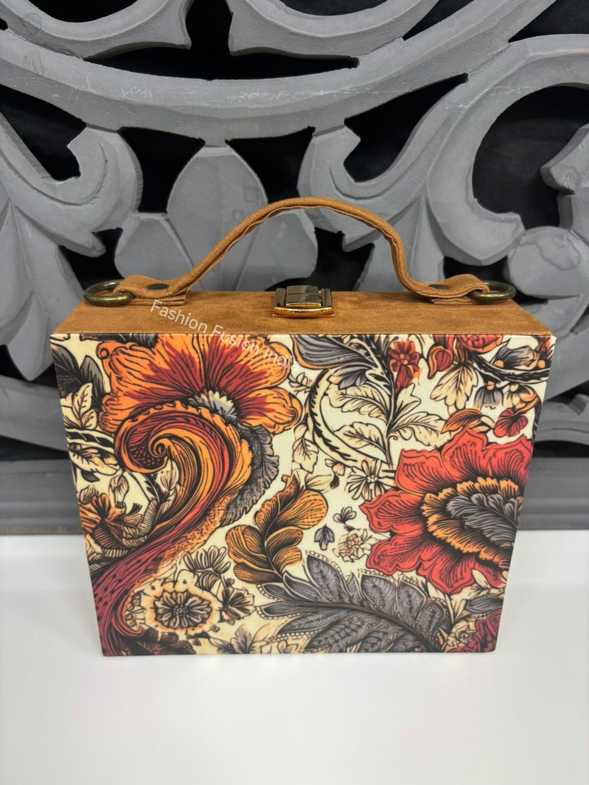 Artistic botanical print wooden clutch bag against carved grey backdrop.