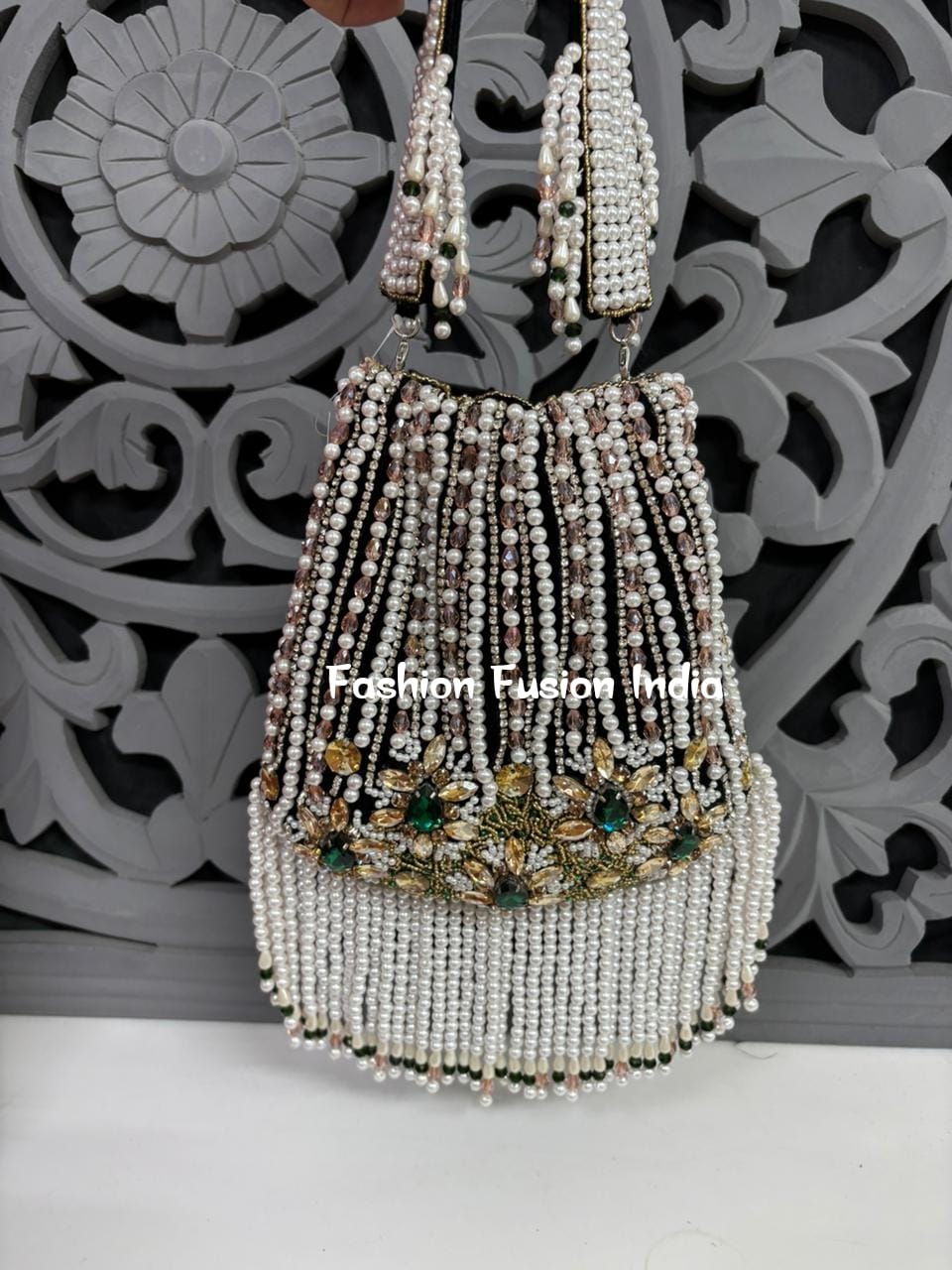 Decorative beaded handbag with floral embellishments against a decorative gray background