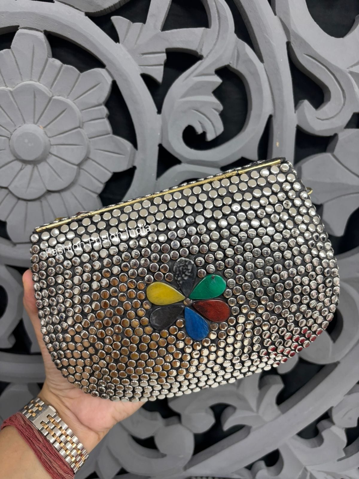 Silver beaded clutch with a colorful butterfly charm held against a decorative gray background