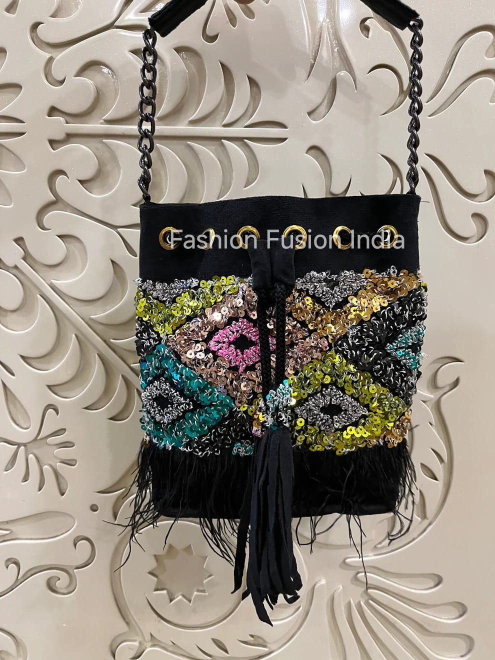 Decorative handbag with colorful patterns and feathers on a textured white background
