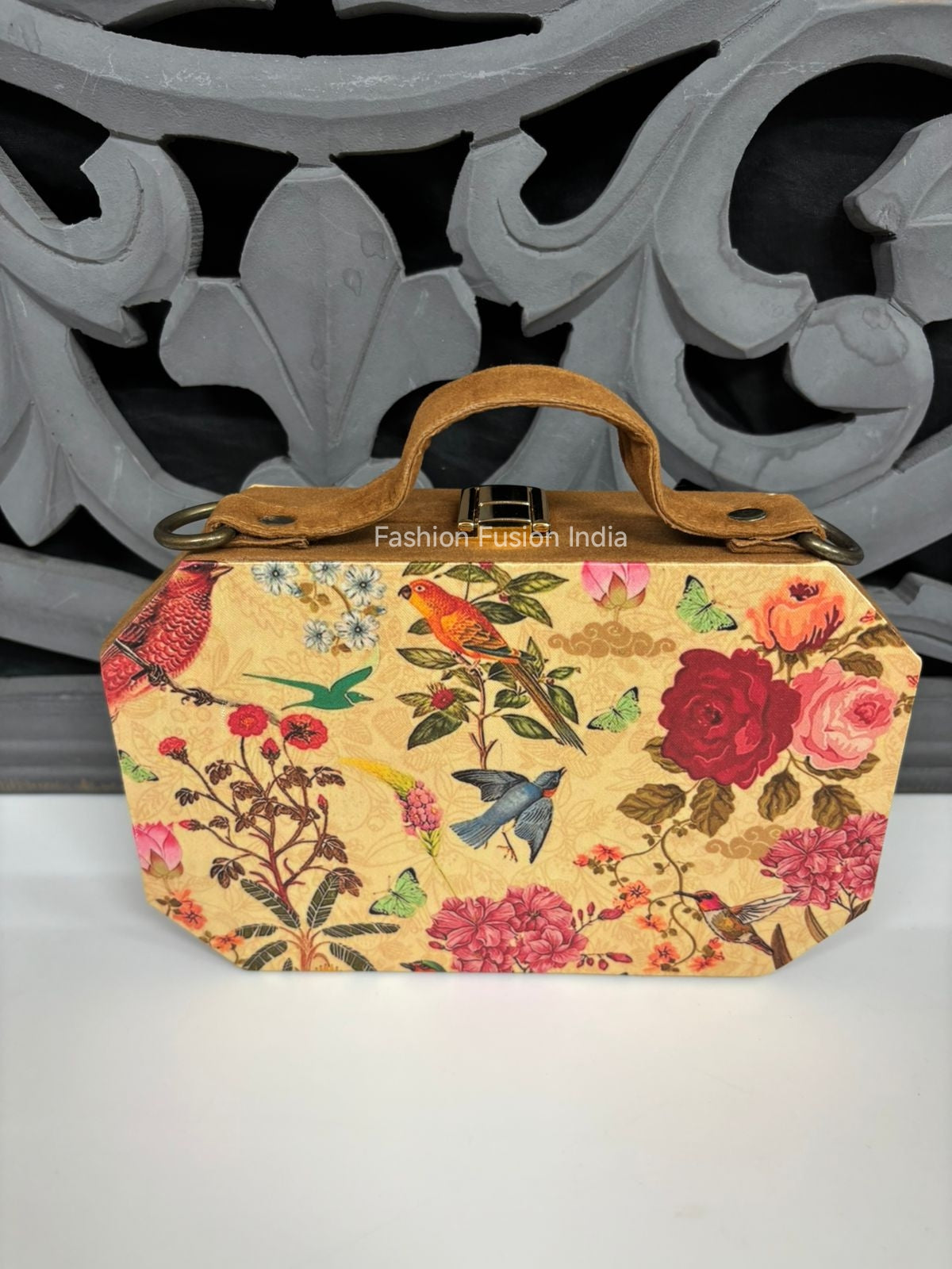 Floral and bird patterned handbag with 'Fashion Fusion India' branding against a decorative metal background.