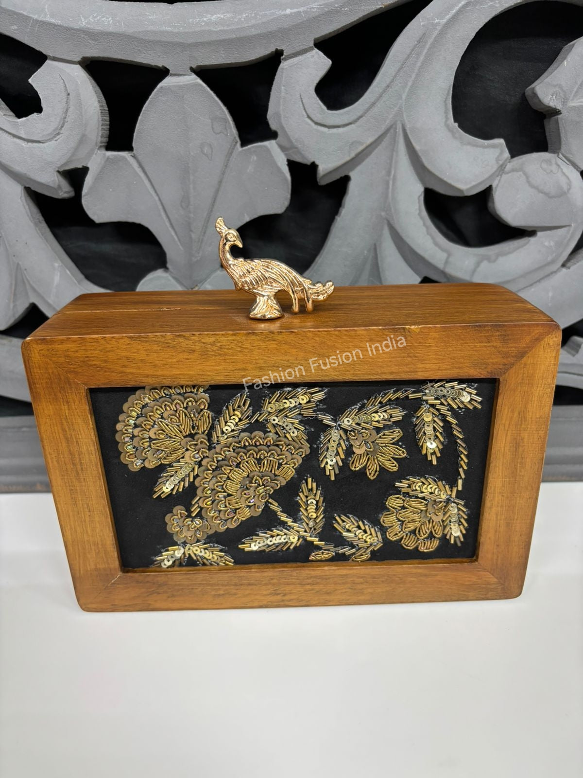 Handcrafted wooden box clutch with gold floral work and metallic peacock clasp.