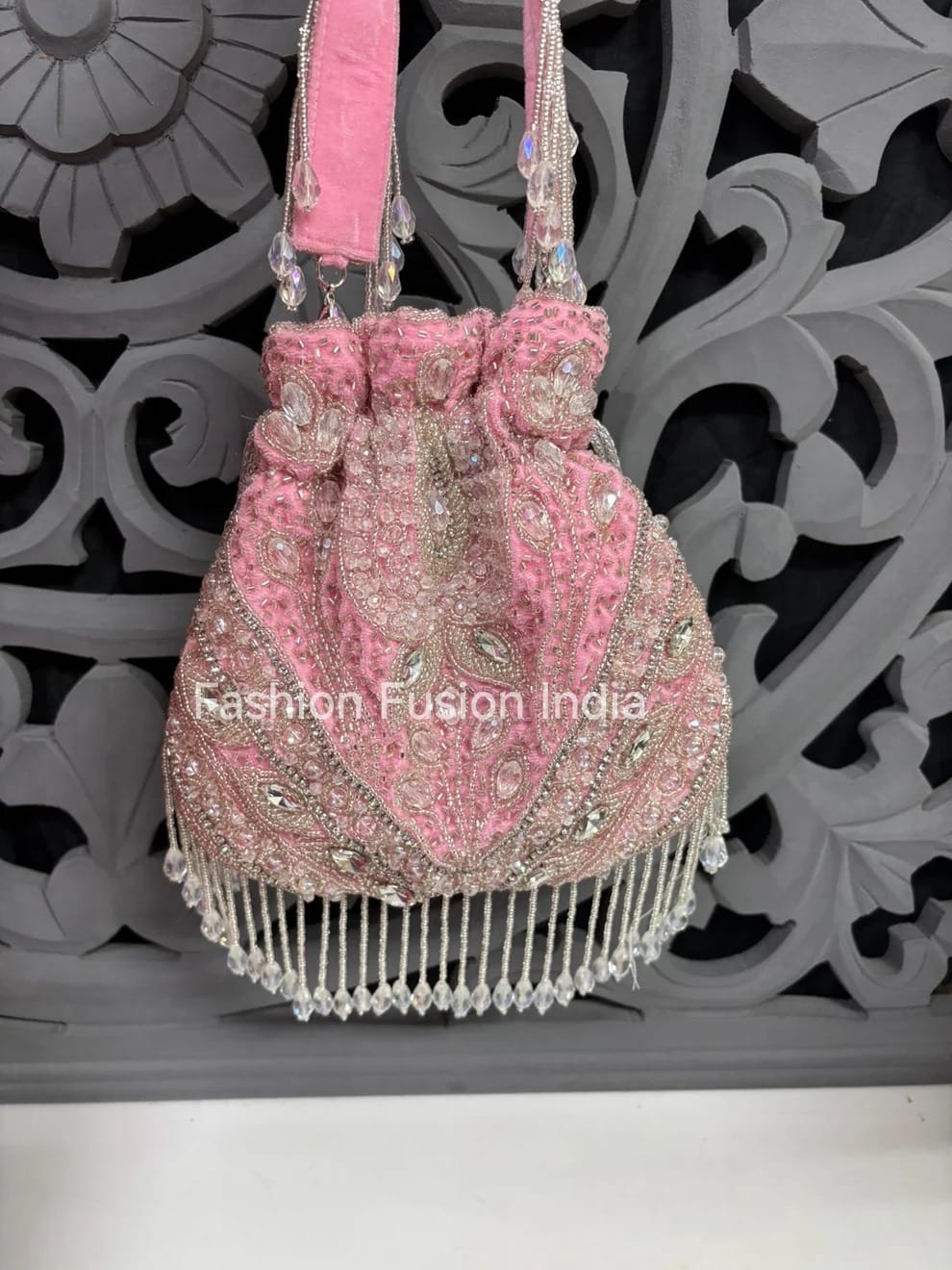 Pink embroidered handbag with fringe details on a decorative background, branded 'Fashion Fusion India'.