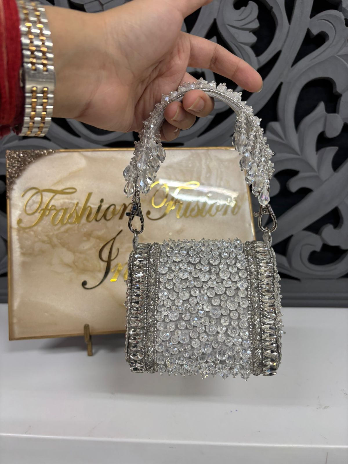 Hand holding a sparkling handbag in front of a 'Fashion Fusion' box.