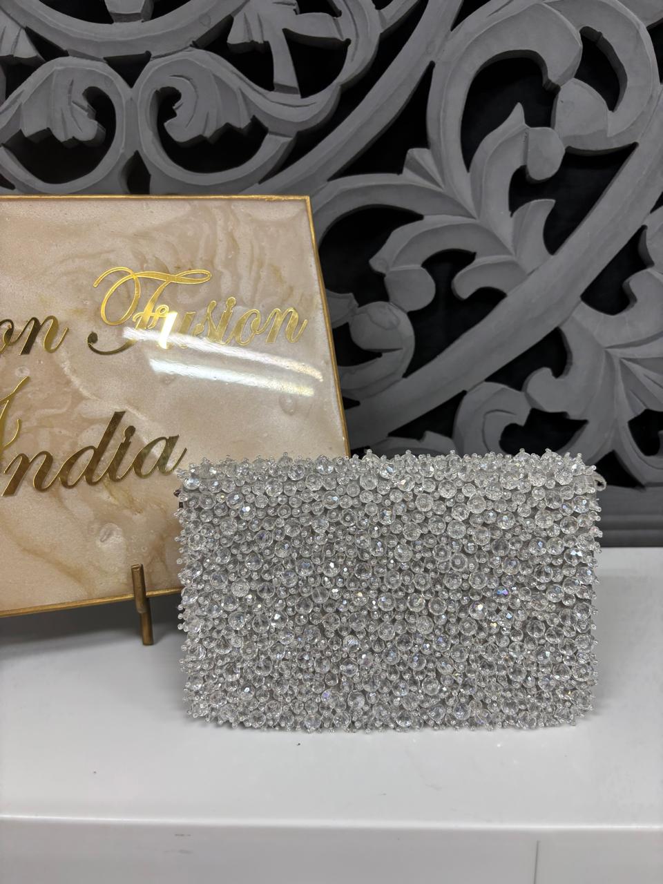 Silver clutch bag on a white surface with decorative background
