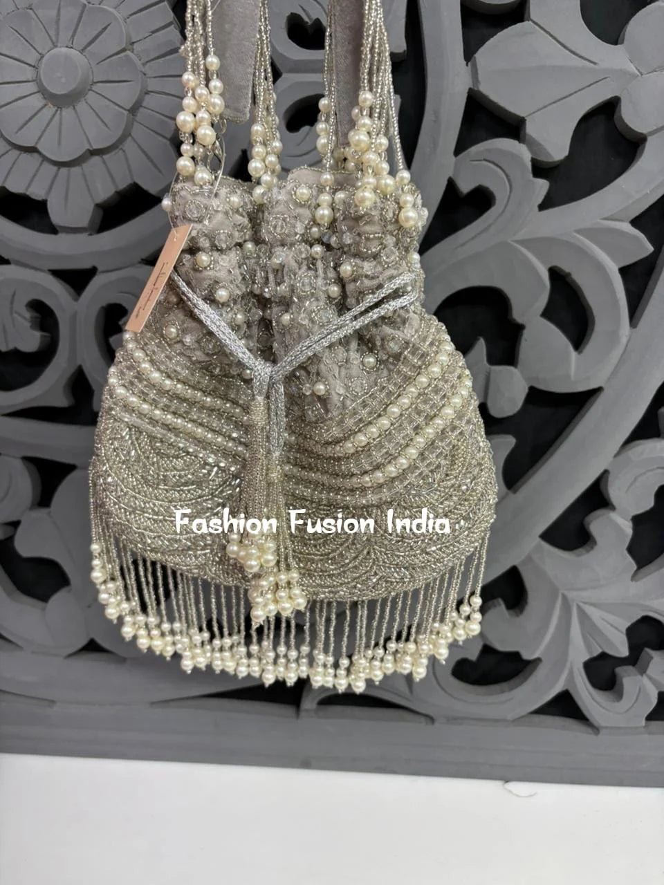 Decorative handbag with pearls against a decorative wall, branded 'Fashion Fusion India'.