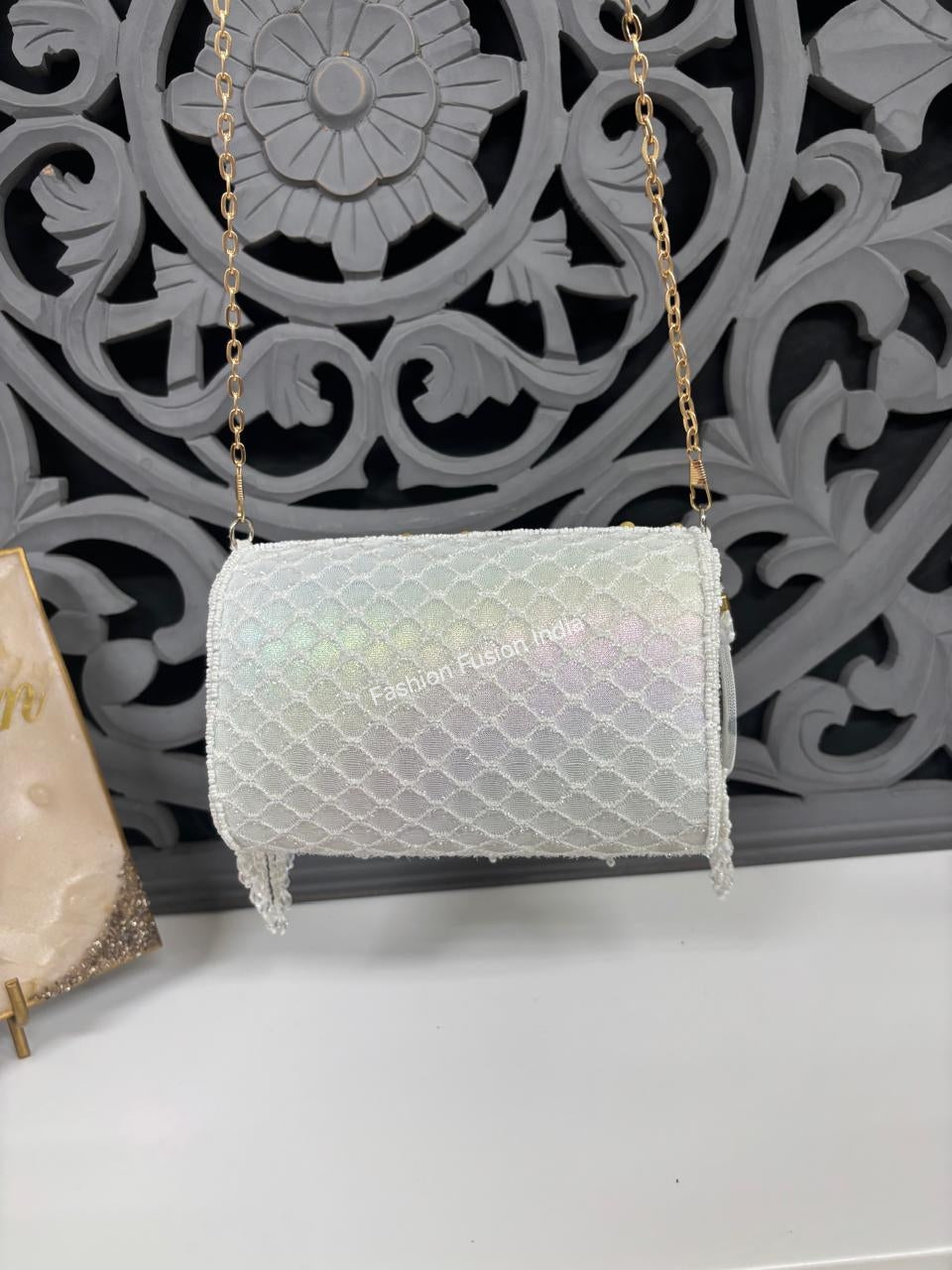 Iridescent handbag with gold chain strap on a decorative wall background