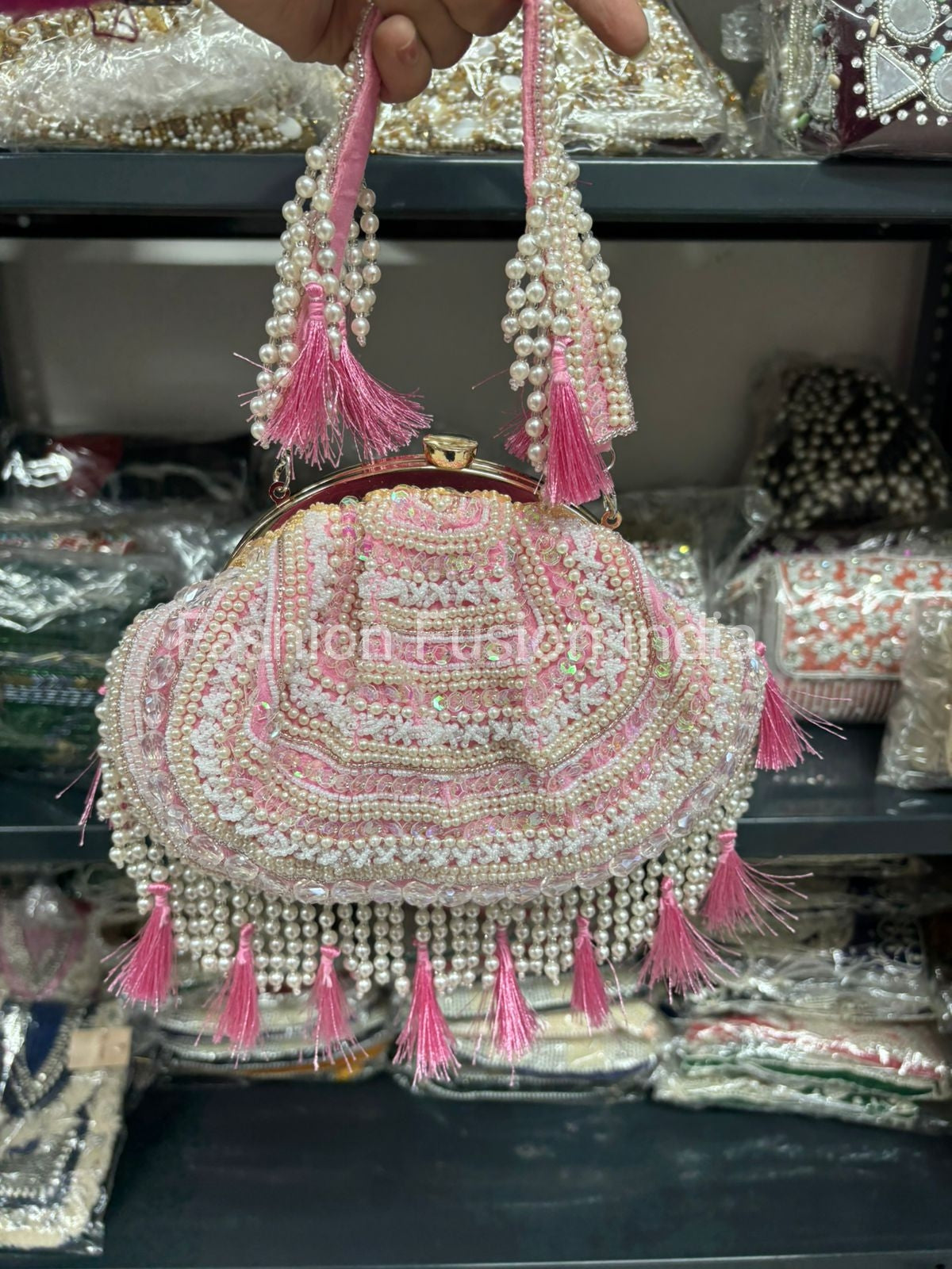 Decorative handbag with pearls and pink tassels on a blurred background