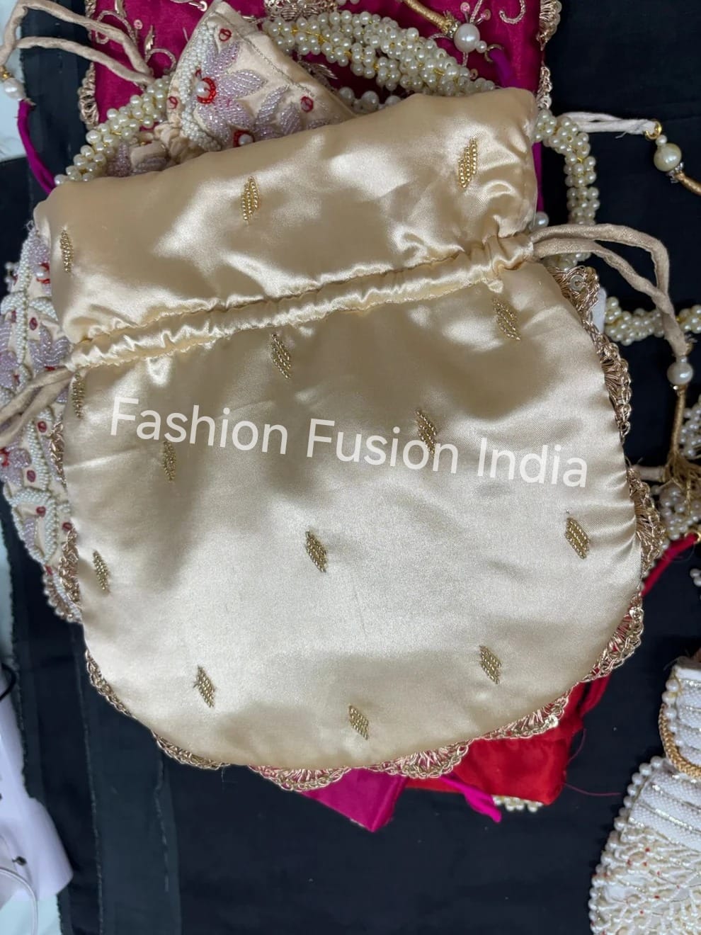 Decorative pouch with gold embroidery on a dark background, branded 'Fashion Fusion India'.