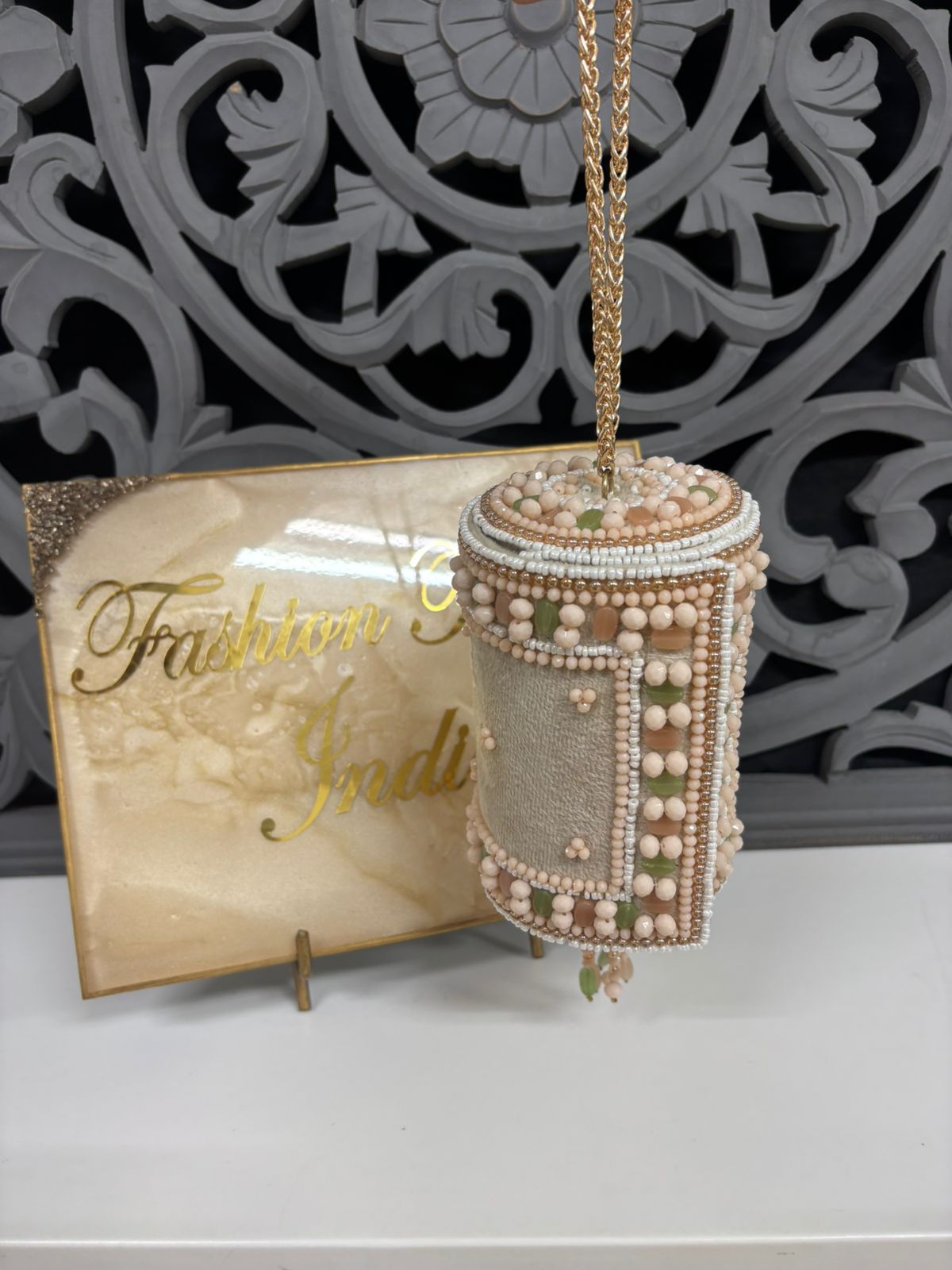 Decorative box with pearls and a gold chain on a stand with 'Fashion India' sign.