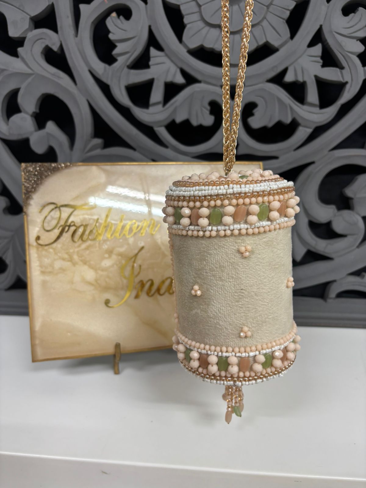 Decorative ornament with beads and chain against a decorative background