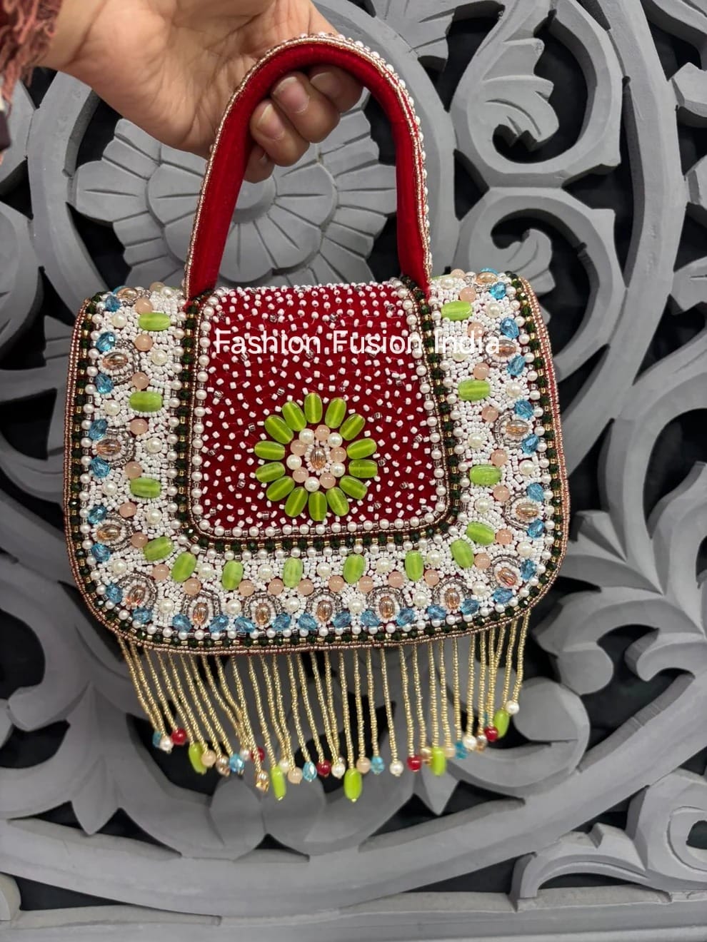 Decorative handbag with intricate designs and beads held against a decorative background.