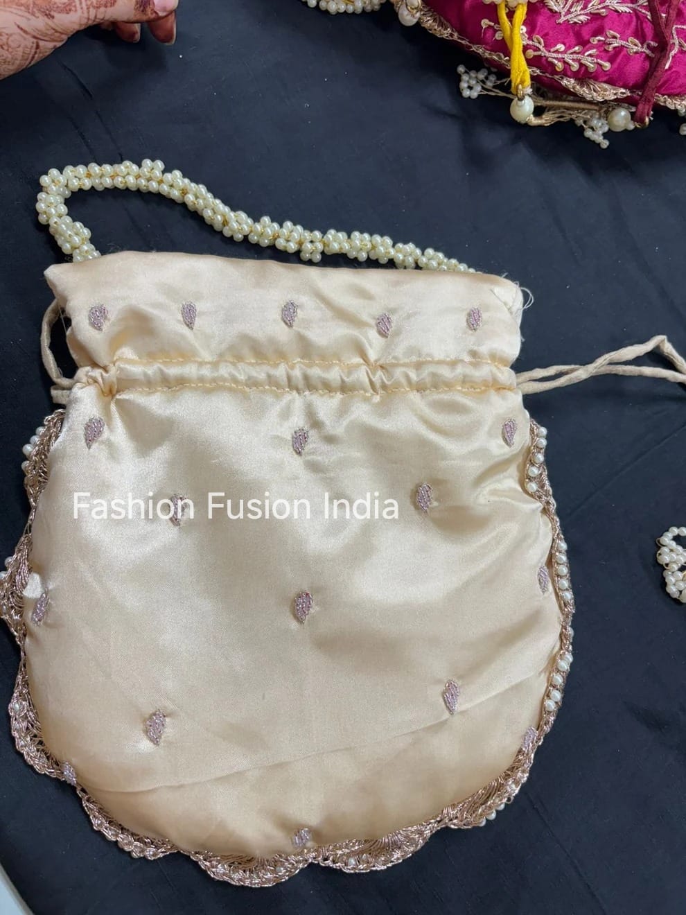 Beige handbag with pearl detailing on a dark surface, branded 'Fashion Fusion India'.