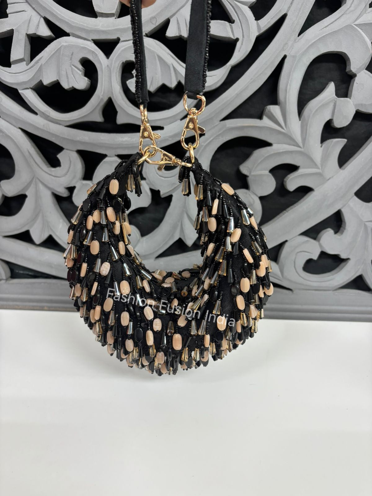 Black and beige beaded handbag on a decorative white and black background