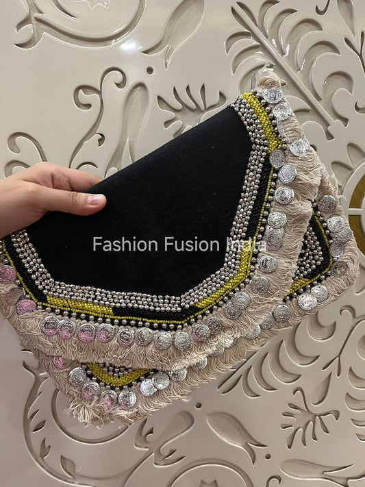 Black clutch with decorative embellishments held by a hand against an ornate background, with 'Fashion Fusion India' branding.