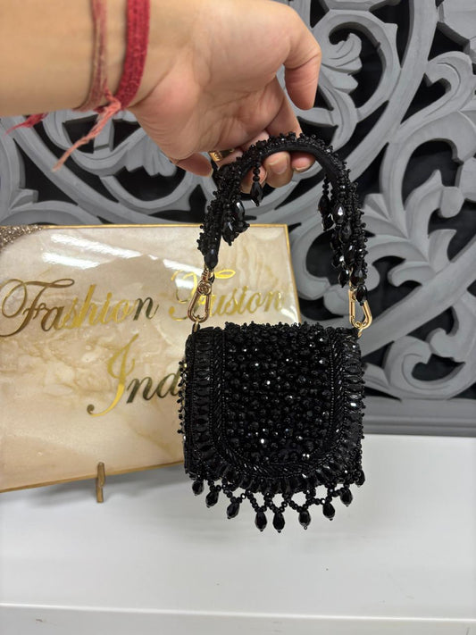 Black beaded handbag held by a hand with a decorative background and 'Fashion East India' sign.