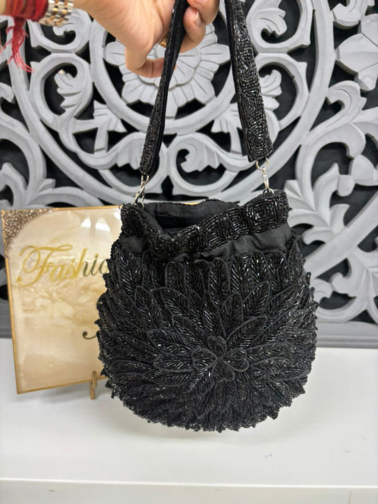 Black woven handbag held by a hand with a decorative background