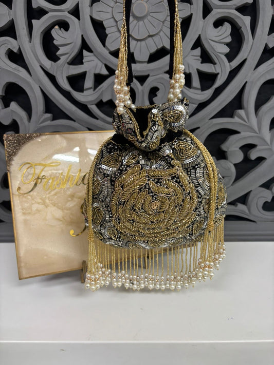 Decorative handbag with intricate designs and pearl details against a decorative wall.