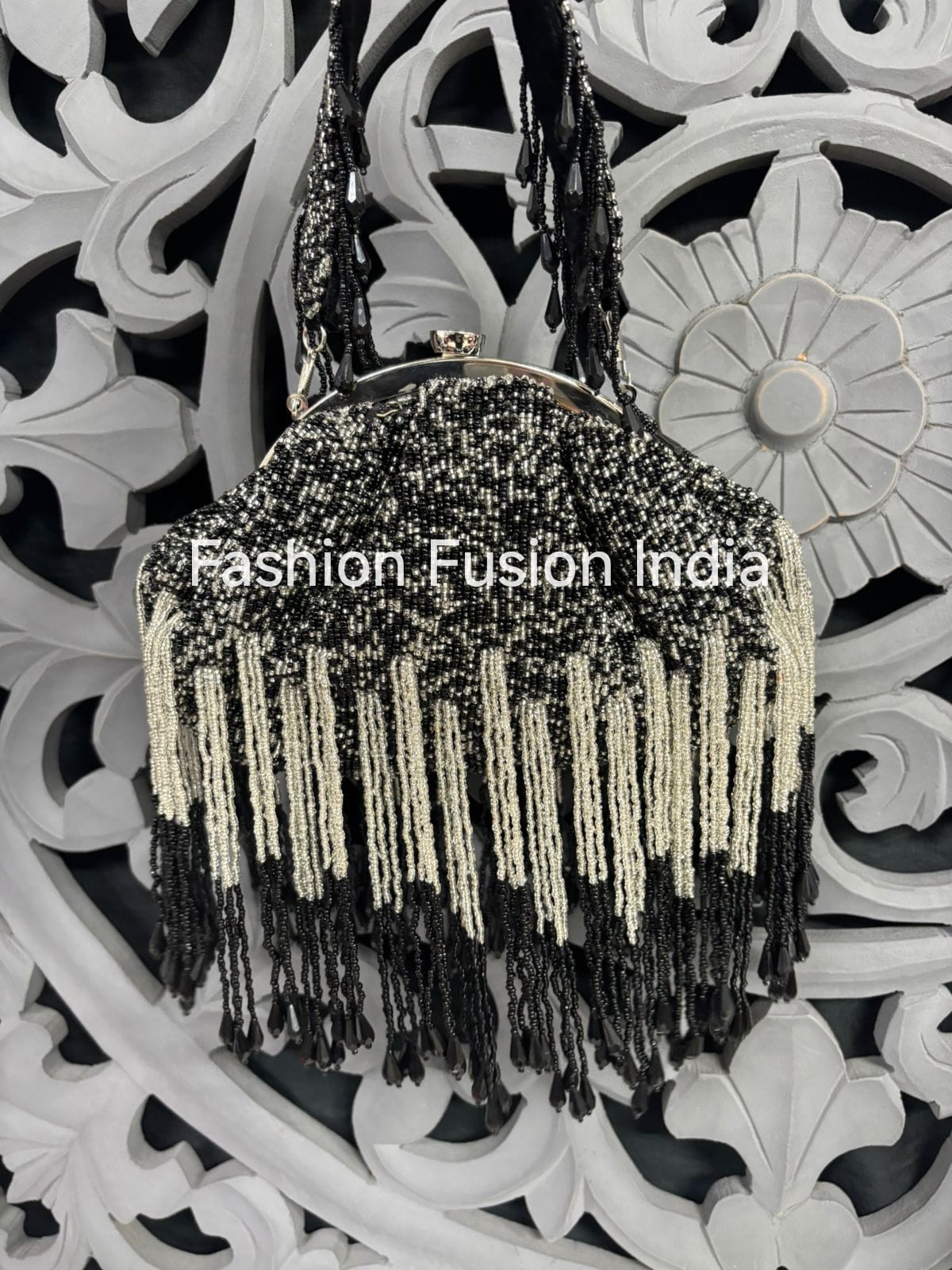Black beaded handbag with fringe details on a decorative white background
