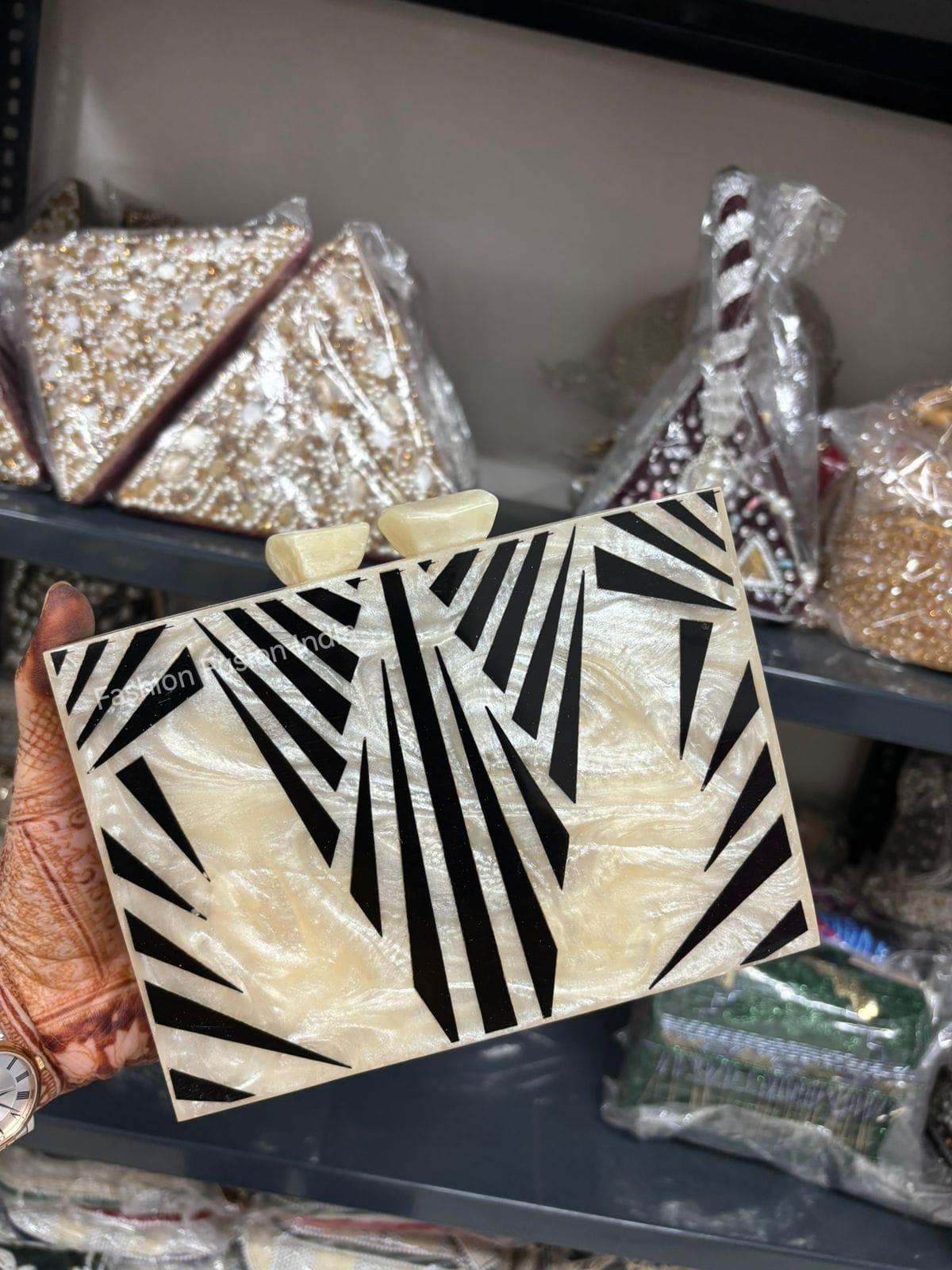 Black and white patterned clutch held by a hand with a blurred background