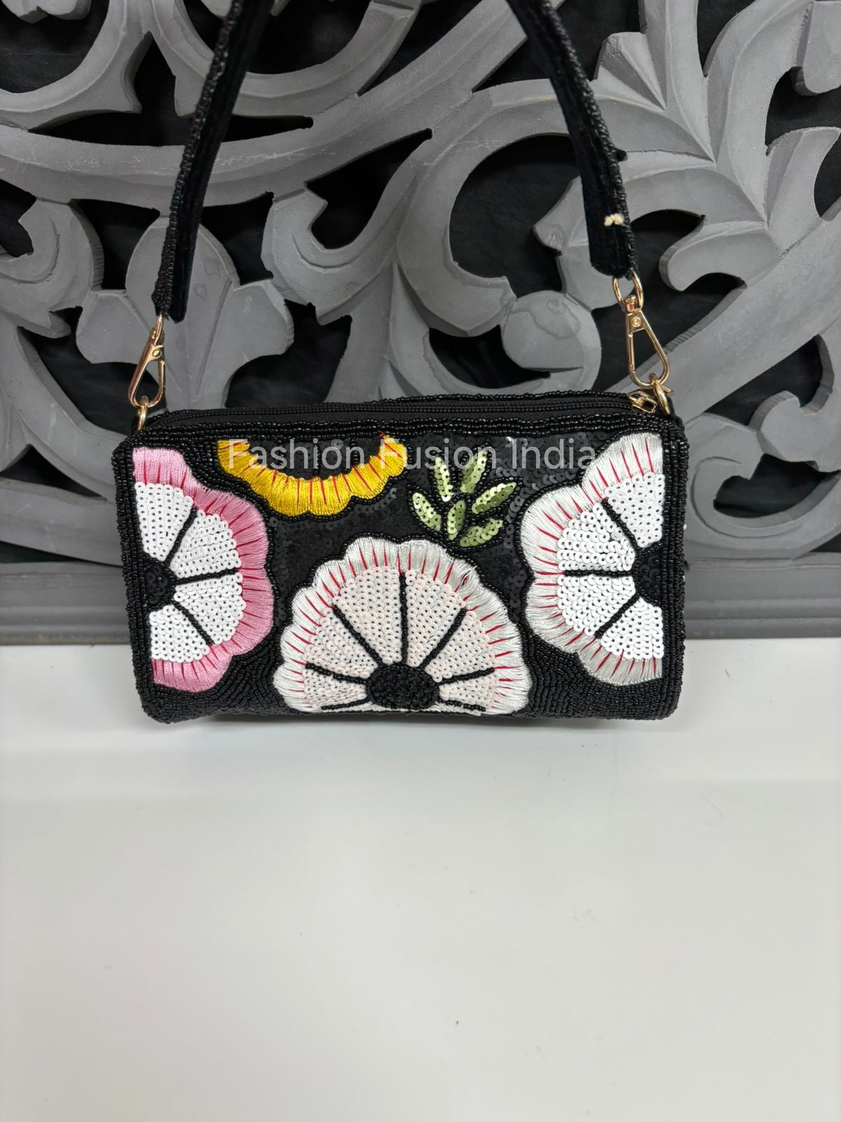 Black handbag with floral patterns and colorful accents on a decorative background