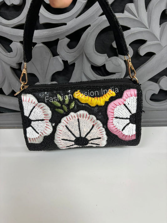 Black clutch bag with floral patterns on a white surface