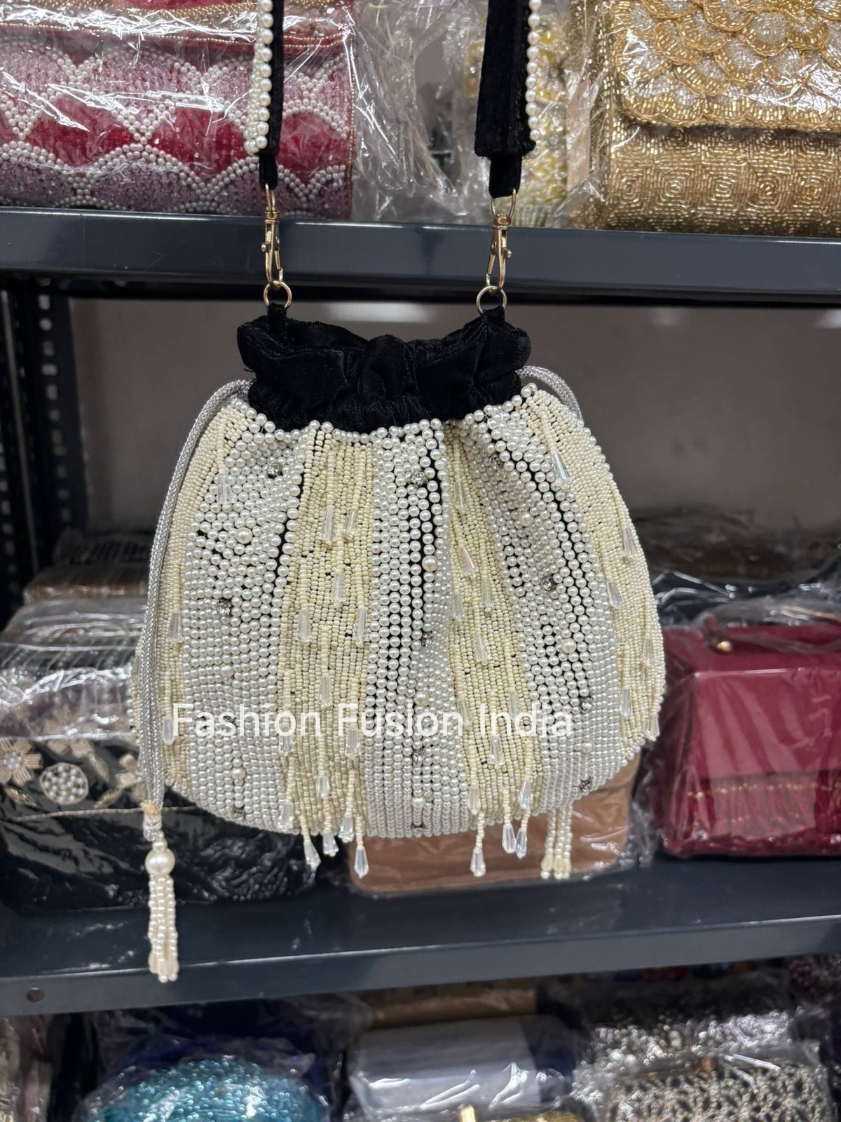 Beaded handbag with black top on a shelf with other bags in the background.