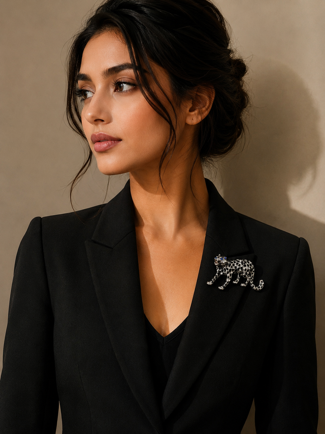 Woman wearing a black blazer with a leopard brooch against a neutral background