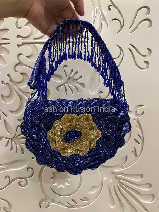 Blue and gold decorative bag held by a hand on a white textured background with 'Fashion Fusion India' branding.
