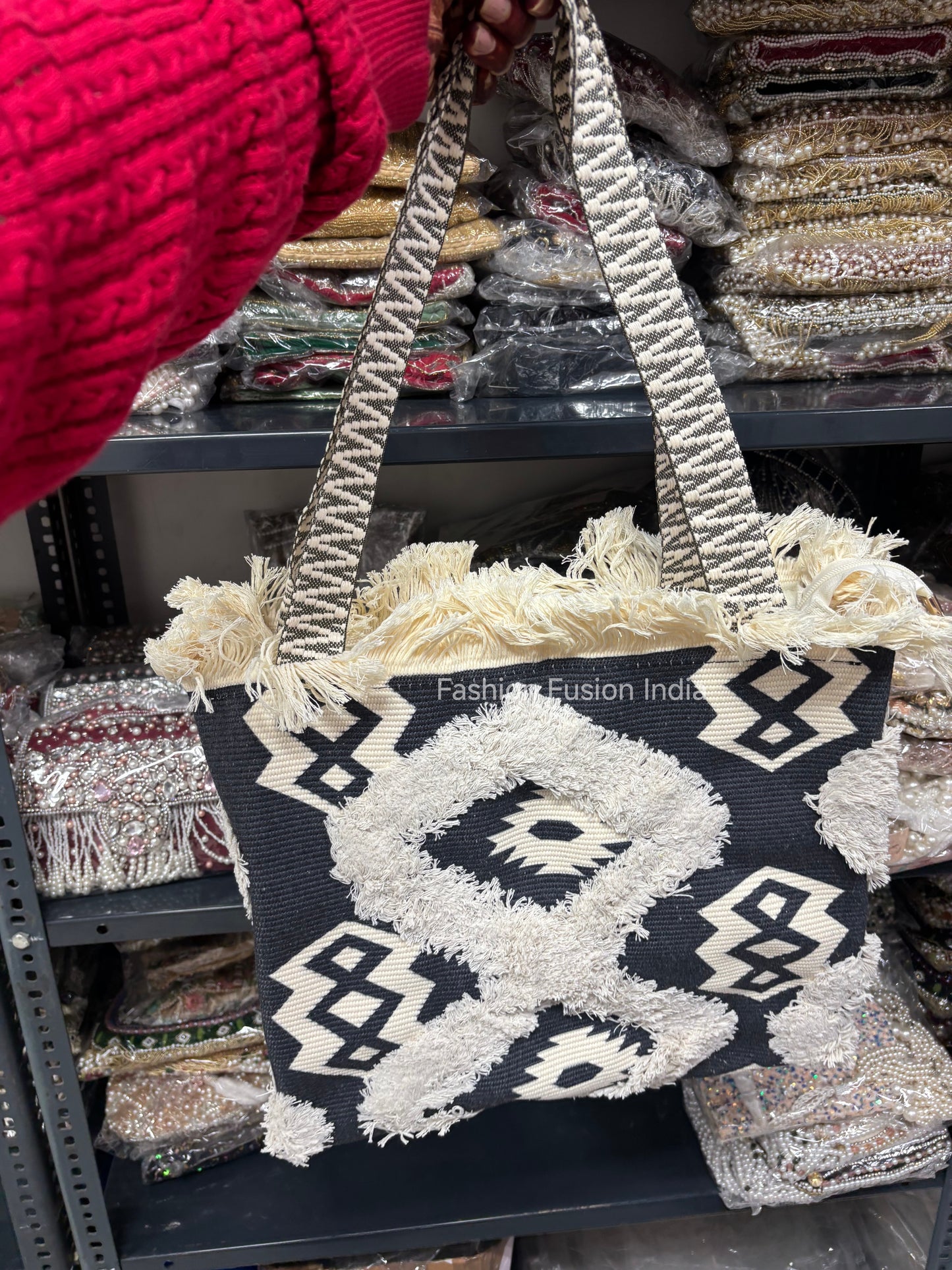 Tote bag with decorative pattern held by a person in a red sweater, with fabric samples in the background.
