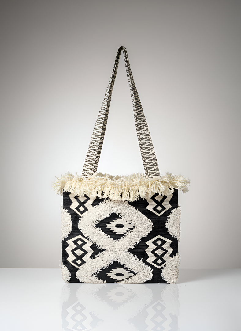 Black and white patterned handbag with tassels on a gray background