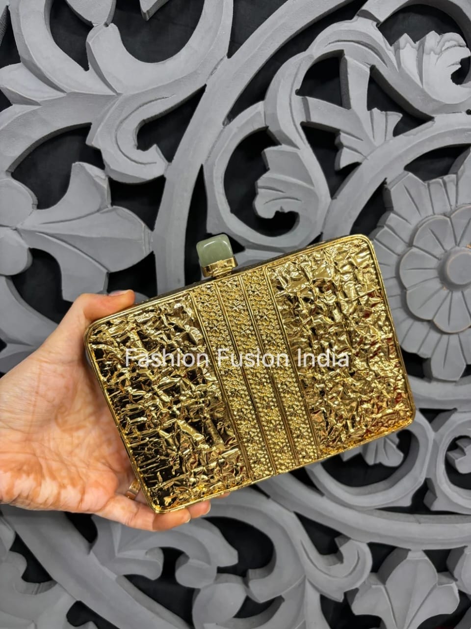 Gold clutch held by a hand with decorative background, 'Fashion Fusion India' brand visible