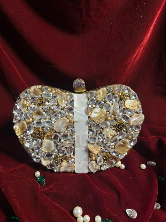 Heart-shaped clutch bag with gemstones on a red fabric background
