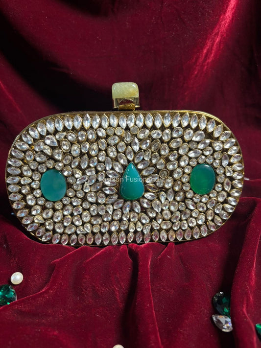 Decorative clutch bag with gemstones and green stones on a red fabric background