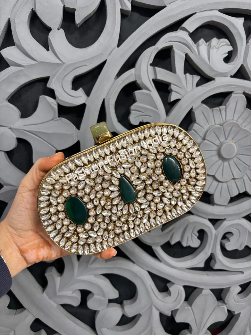 Elegant clutch with decorative elements held against an ornate background