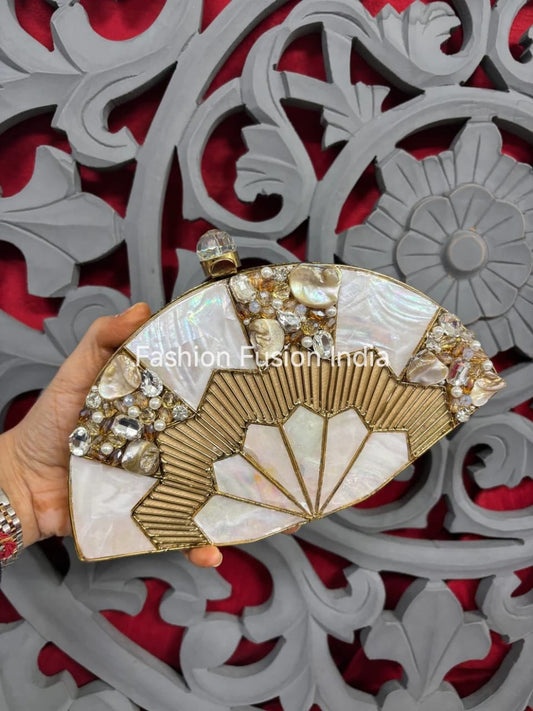 Decorative clutch with fan design and embellishments held against a decorative red and gray background.
